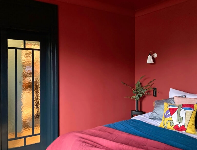 Sypialnia z czerwonymi ścianami i sufitem, czarne drzwi ze szkłem